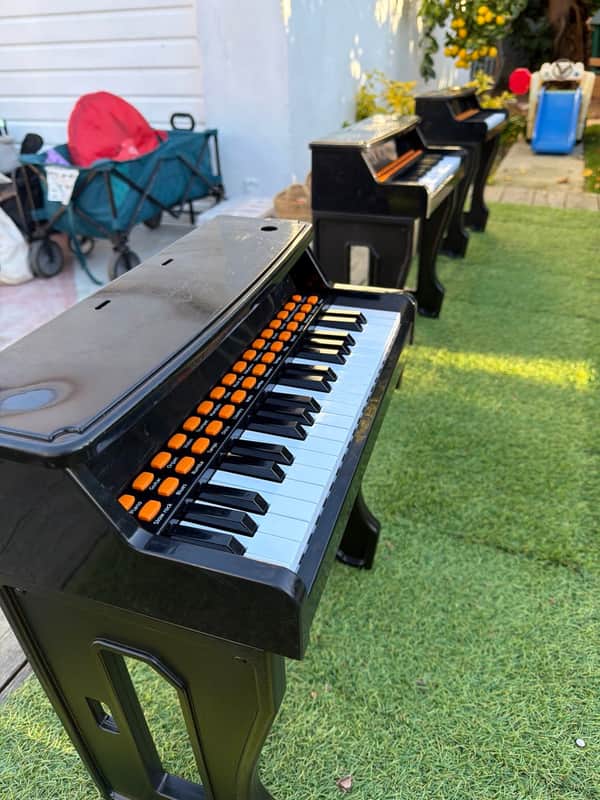 A row of children's toy pianos set out on the grass for music play